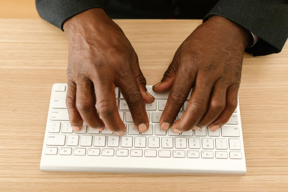 A close-up of hands typing on a laptop keyboard.