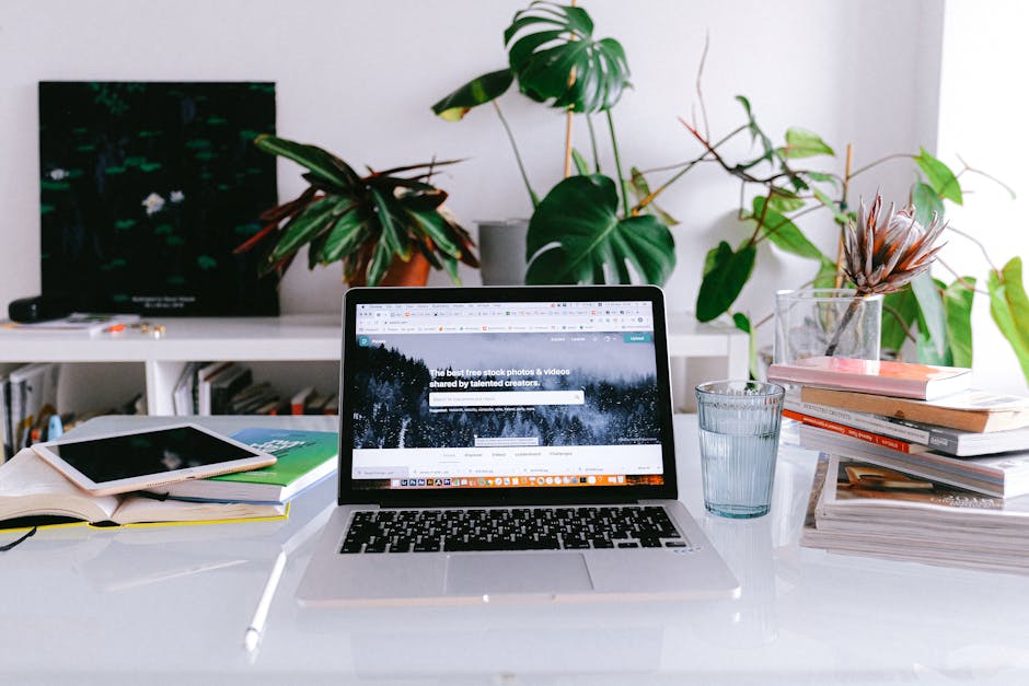 A self-employed person typing at a laptop in a bright home office.